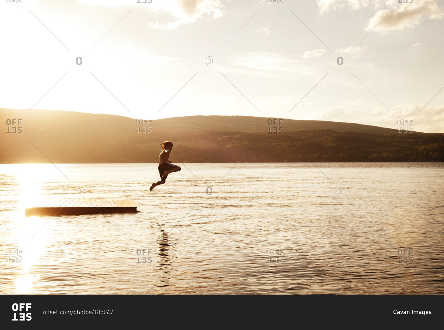 A boy jumps off a floating dock on a lake
