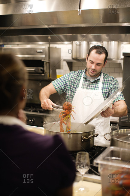 A cooking student removes his lobster from a pot