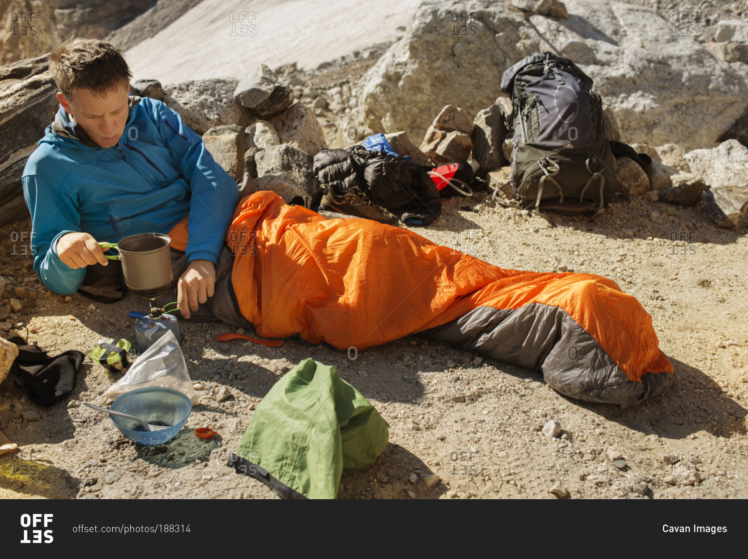 Man in sleeping bag operating camp stove