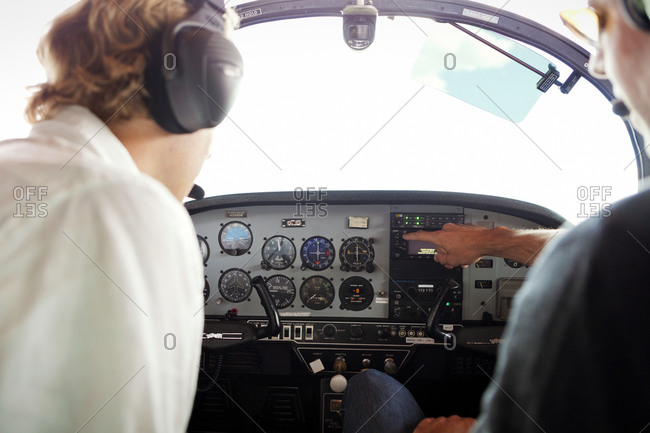 Two pilots consulting dials in a small airplane cockpit