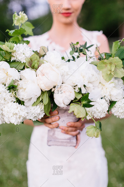 Bride holding urn of white flowers