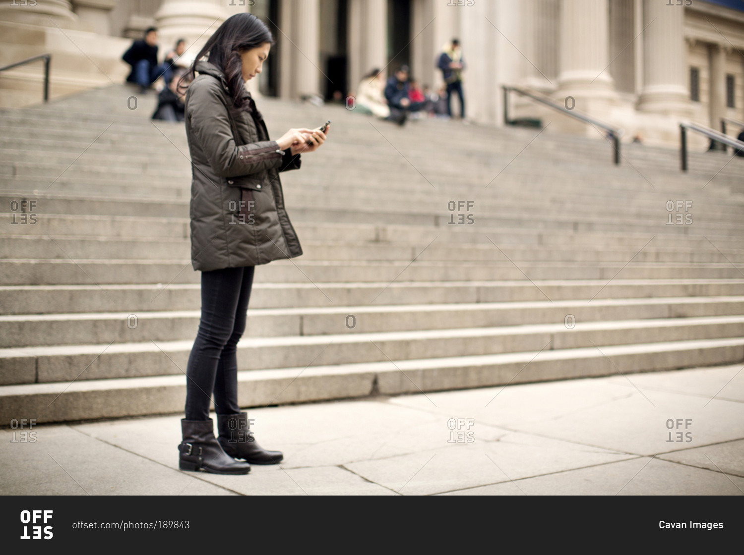 Woman using smartphone by museum steps