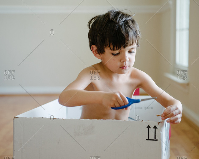 Young boy cutting a box with a scissor