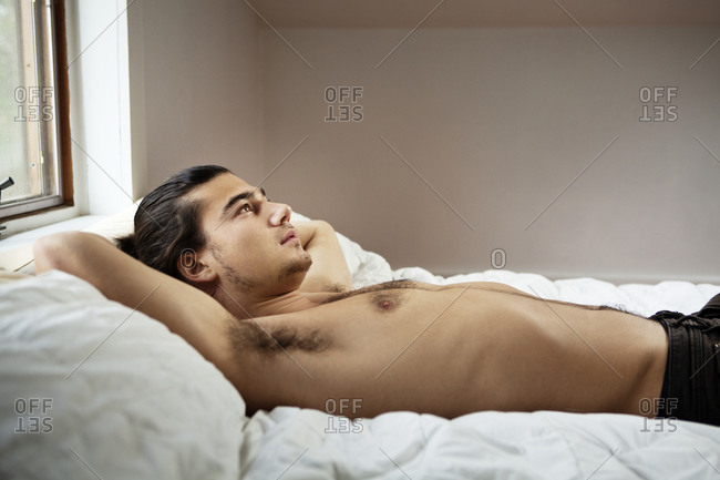 Man laying awake in bed shirtless
