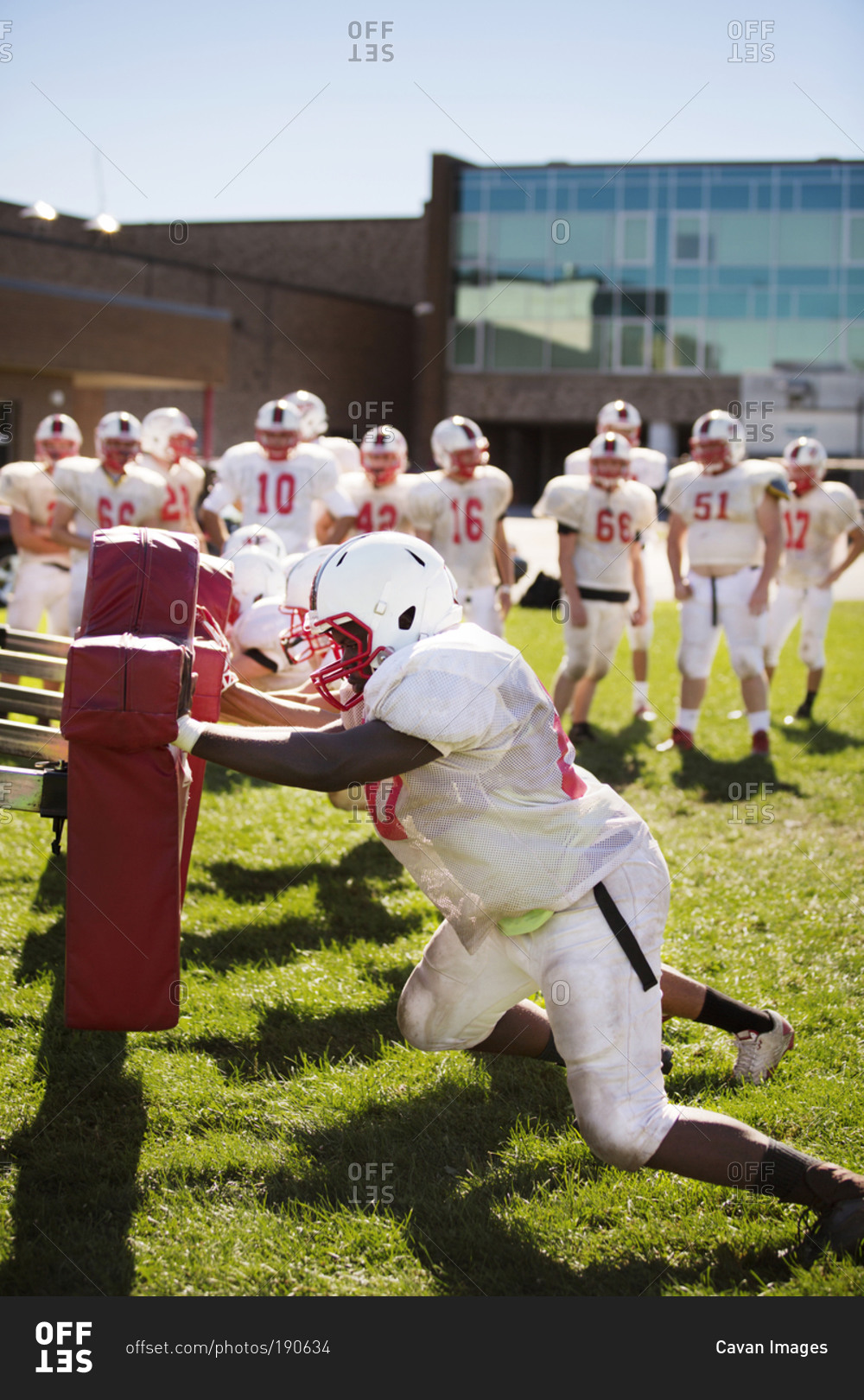 A high school football team practices using tackling dummies