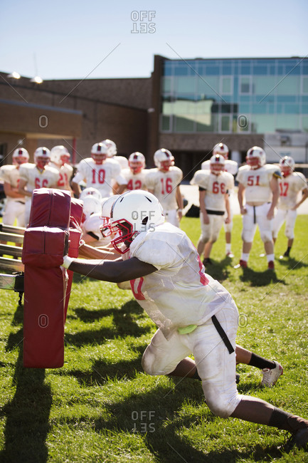 A high school football team practices using tackling dummies
