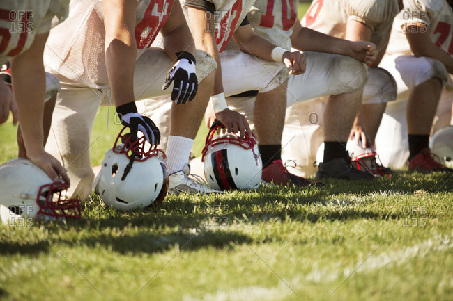 A high school football team takes a knee stock photo - OFFSET