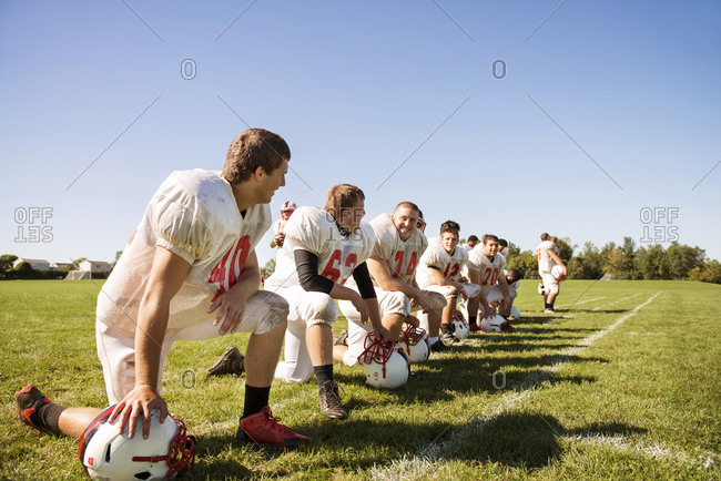 Kneeling football players laugh with one another