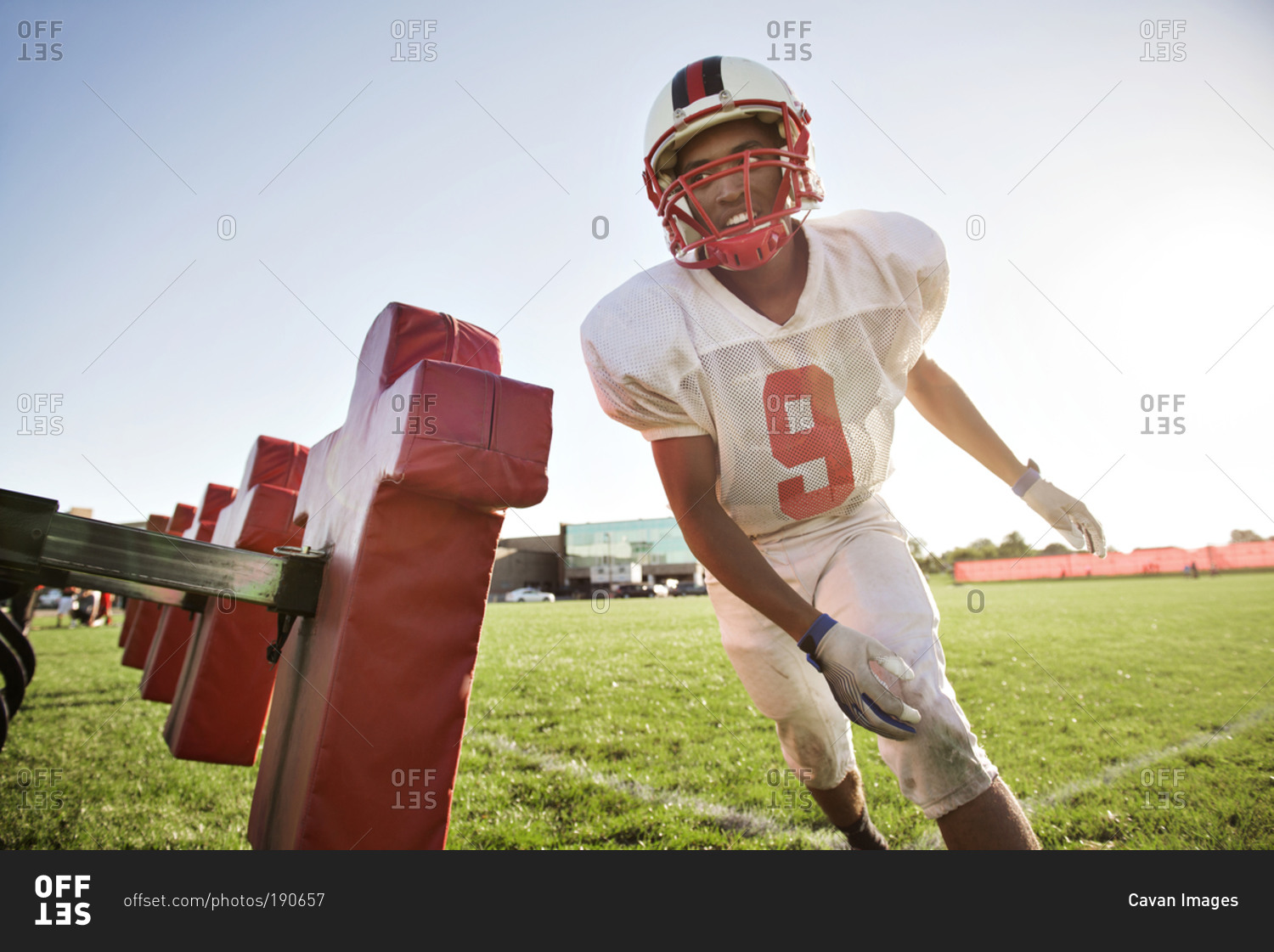 A high school football player runs past a tackling dummy
