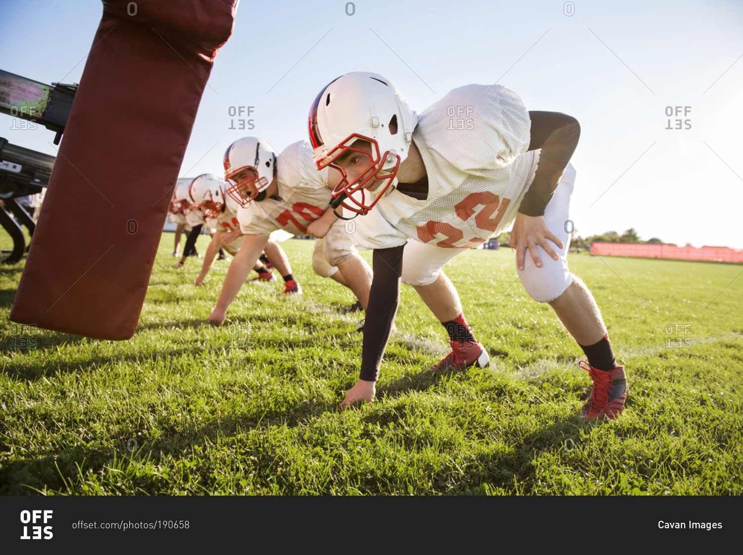 High school football players prepare to tackle a dummy