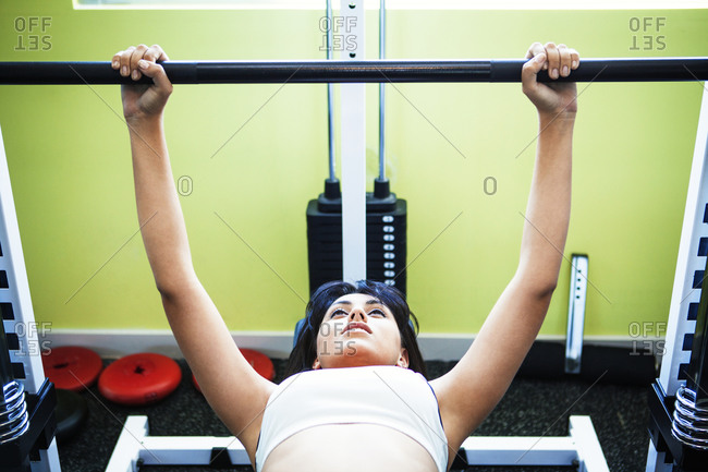 A woman lifts weights on a weight bench