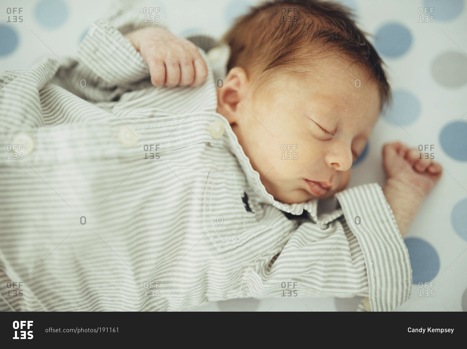 Newborn baby in button up shirt sleeping on back