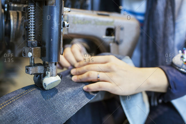 Hands of woman sewing denim with industrial machine
