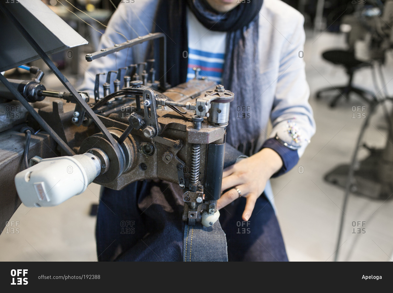 Woman sewing seam with denim at industrial machine