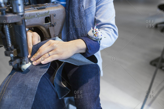 Woman sewing denim fabric at industrial machine