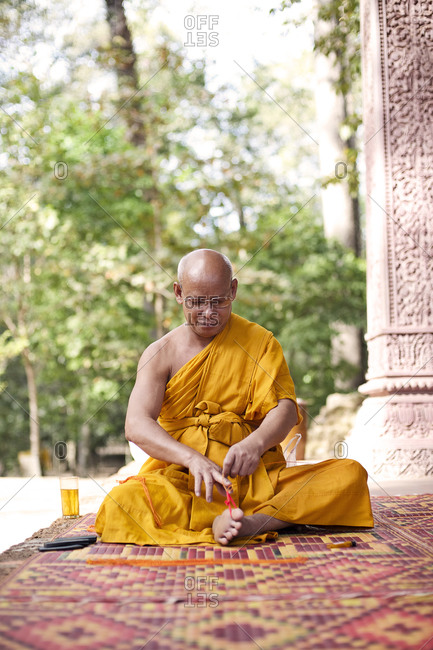 Siem Reap, Cambodia - December 19, 2014: Buddhist monk weaving bracelets