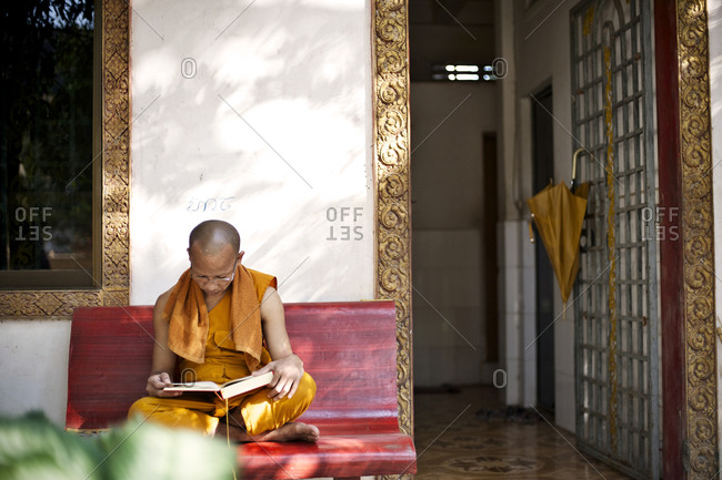 Siem Reap, Cambodia - December 22, 2014: Buddhist monk reading on a bench