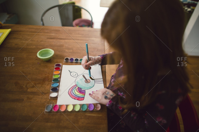 A little girl paints an imagined animal