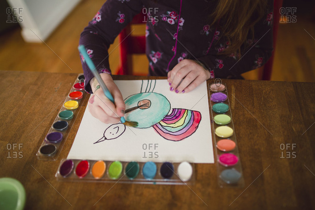 A little girl paints with watercolor