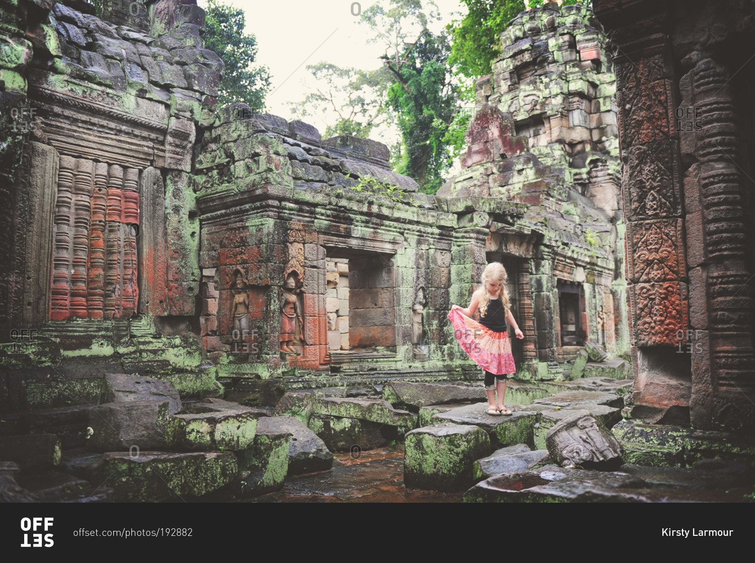 A young girl walking on stones of ancient temple ruins, Cambodia