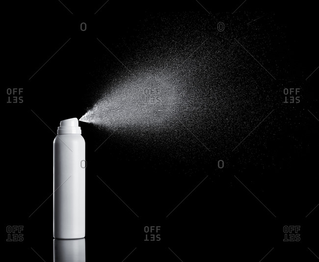 White spraying aerosol can in front of black background