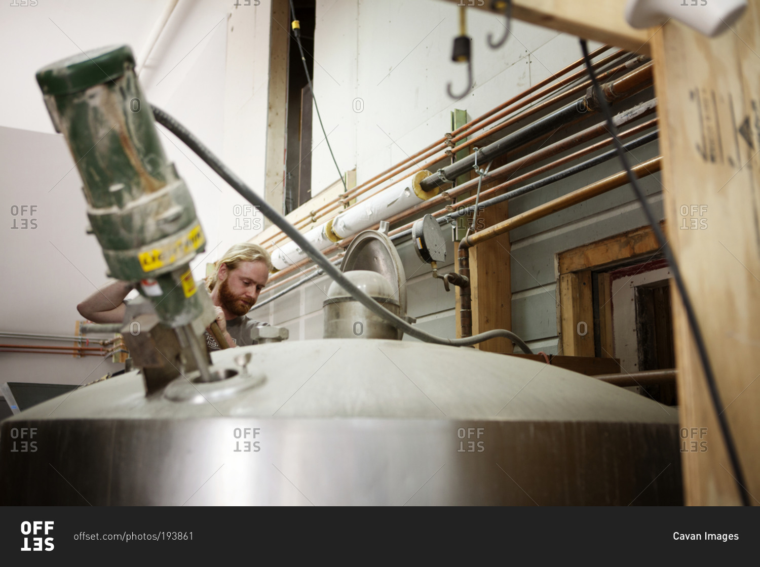 A man mixes fermenting whiskey in a tank stock photo OFFSET