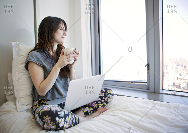 Woman wearing bra and panties looking through the window of her