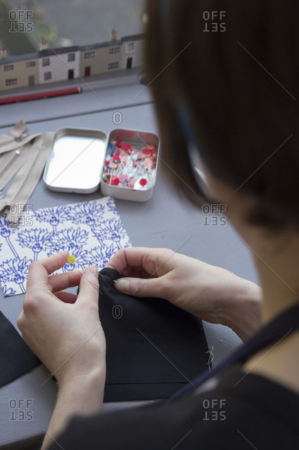 Woman pinning material seams together for sewing