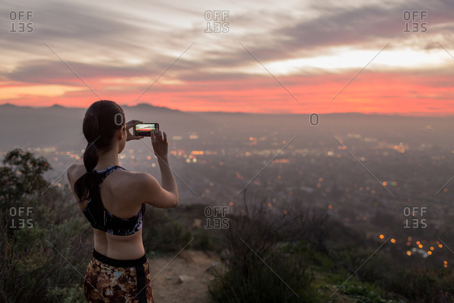 Young woman taking pictures at sundown