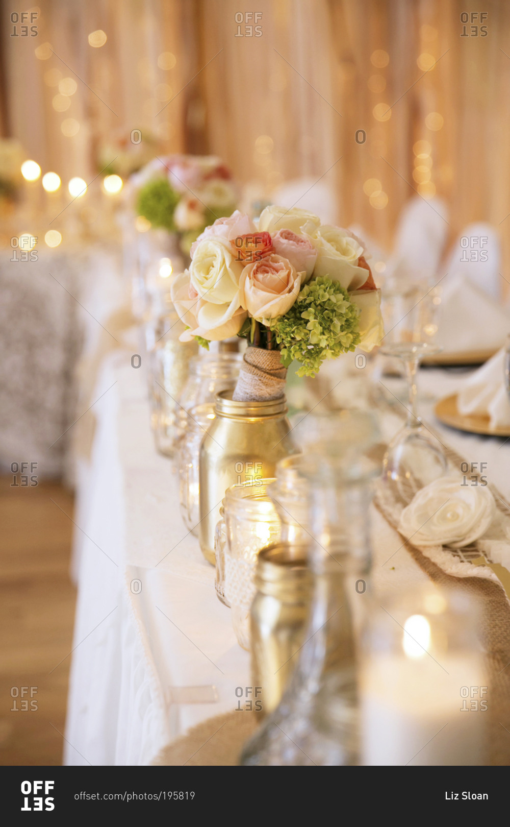 Mason jars, candles, and flowers decorating tables set for a wedding party