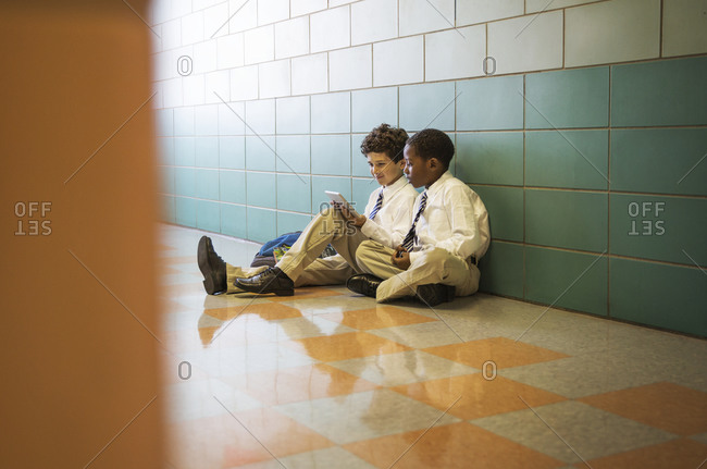 School boys using digital tablet in a hallway of a school