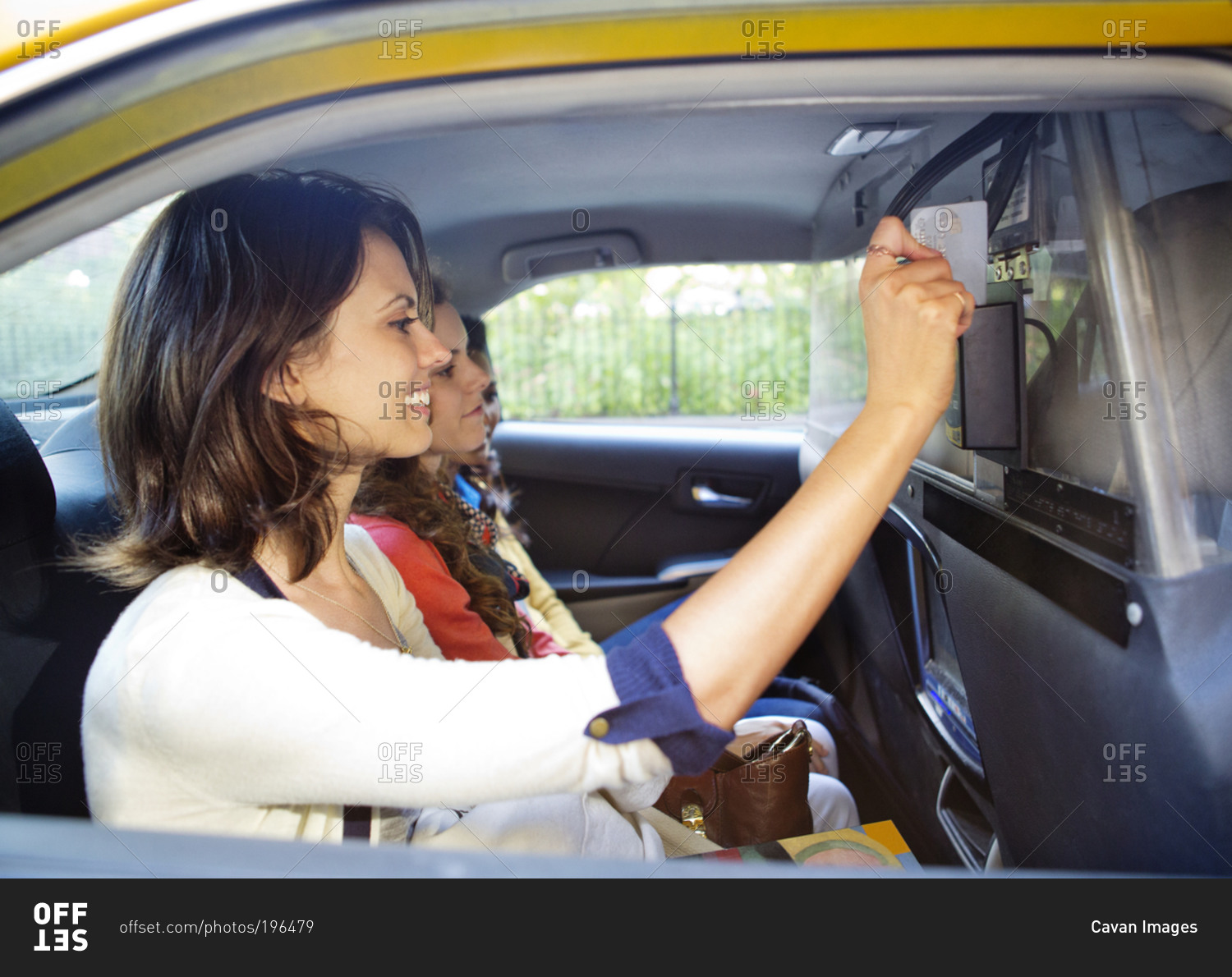 A woman swipes her credit card in the back of a taxi