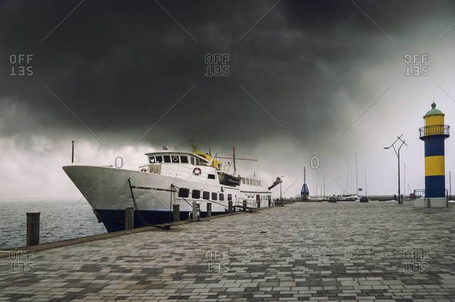 Germany, Schleswig-Holstein, Eckernfoerde - February 14, 2015: Cruise vessel at port under dark cloud