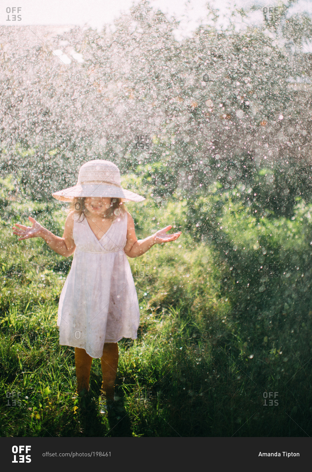 Water raining over girl in white hat and dress