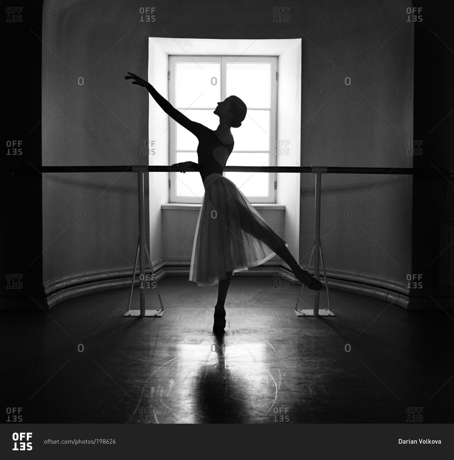 Female ballet dancer at barre in of window stock photo - OFFSET
