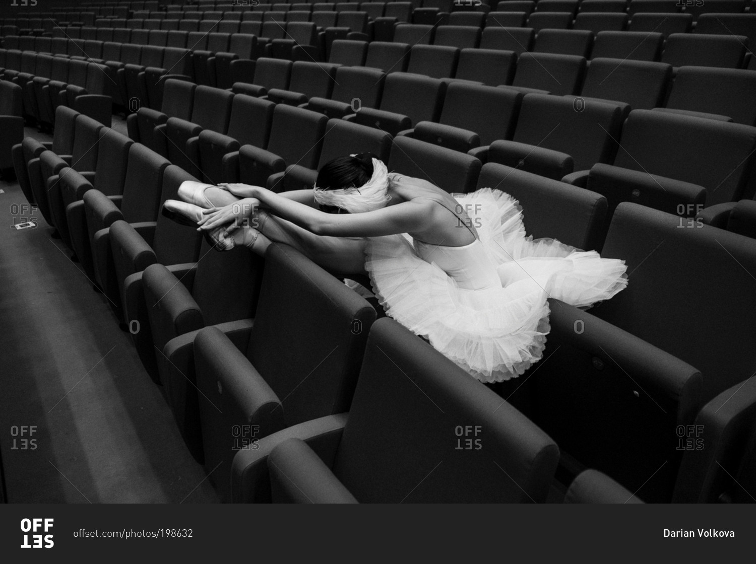 Costumed ballet dancer resting in theater seats