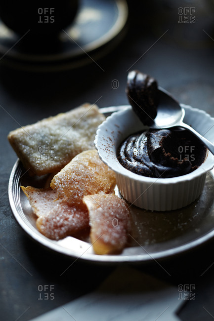 Sugared cookies and citrus rind on plate with dark chocolate mousse