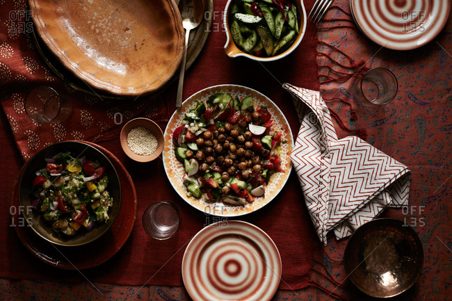 Middle Eastern salads on red linens with dishes