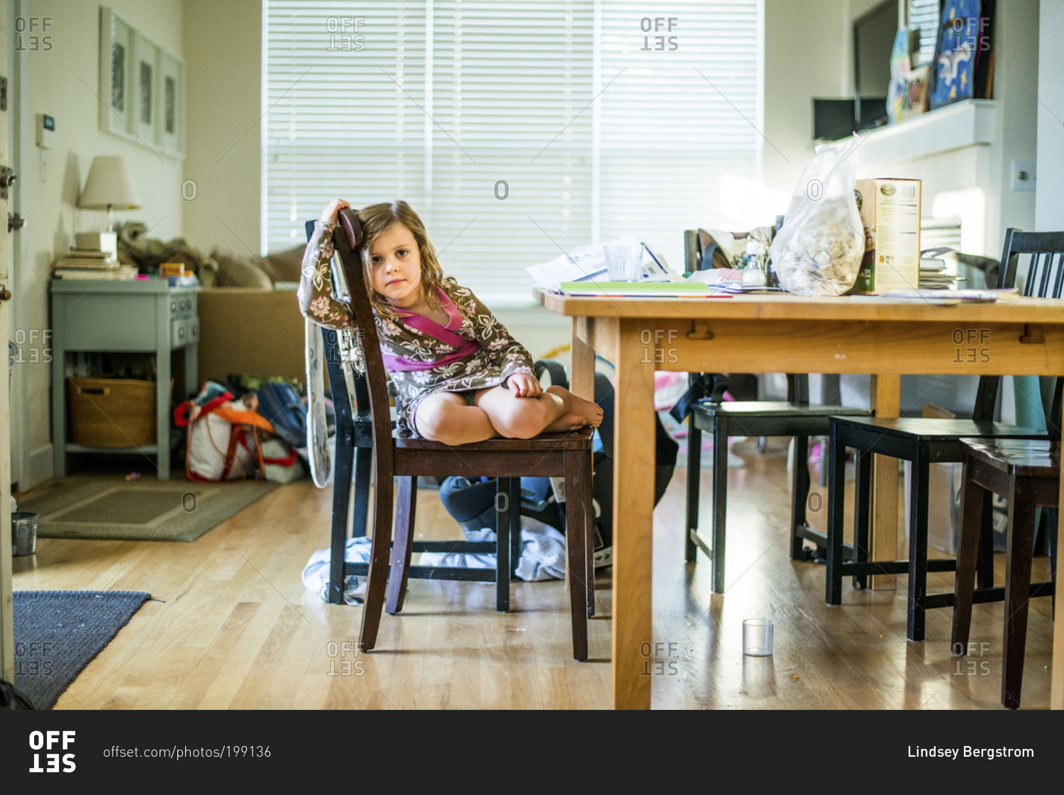 Little girl relaxing in chair while doing homework stock photo - OFFSET