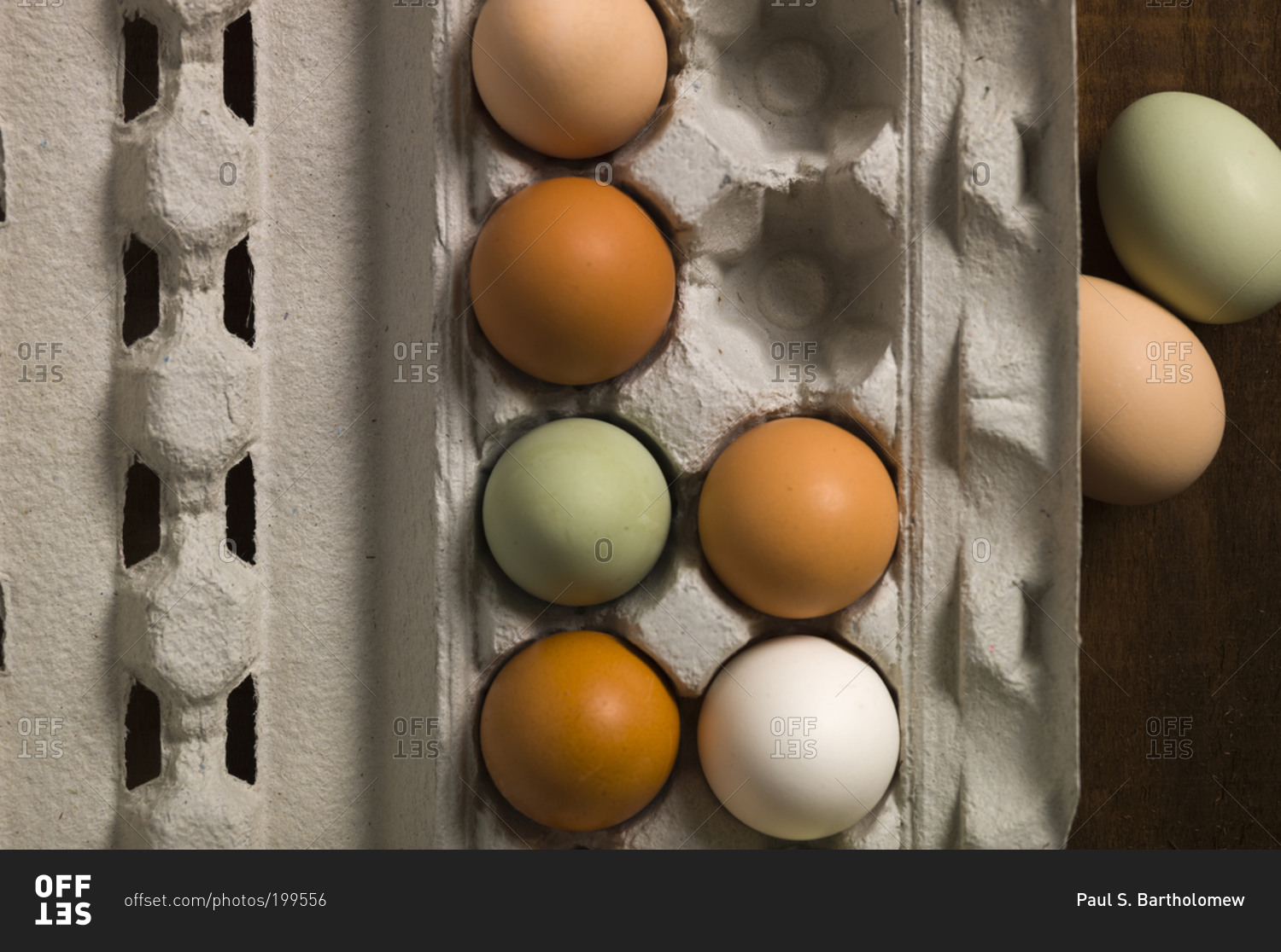 Overhead view of colorful chicken eggs in a paper carton