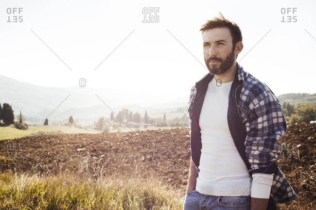Man in flannel standing in rural field