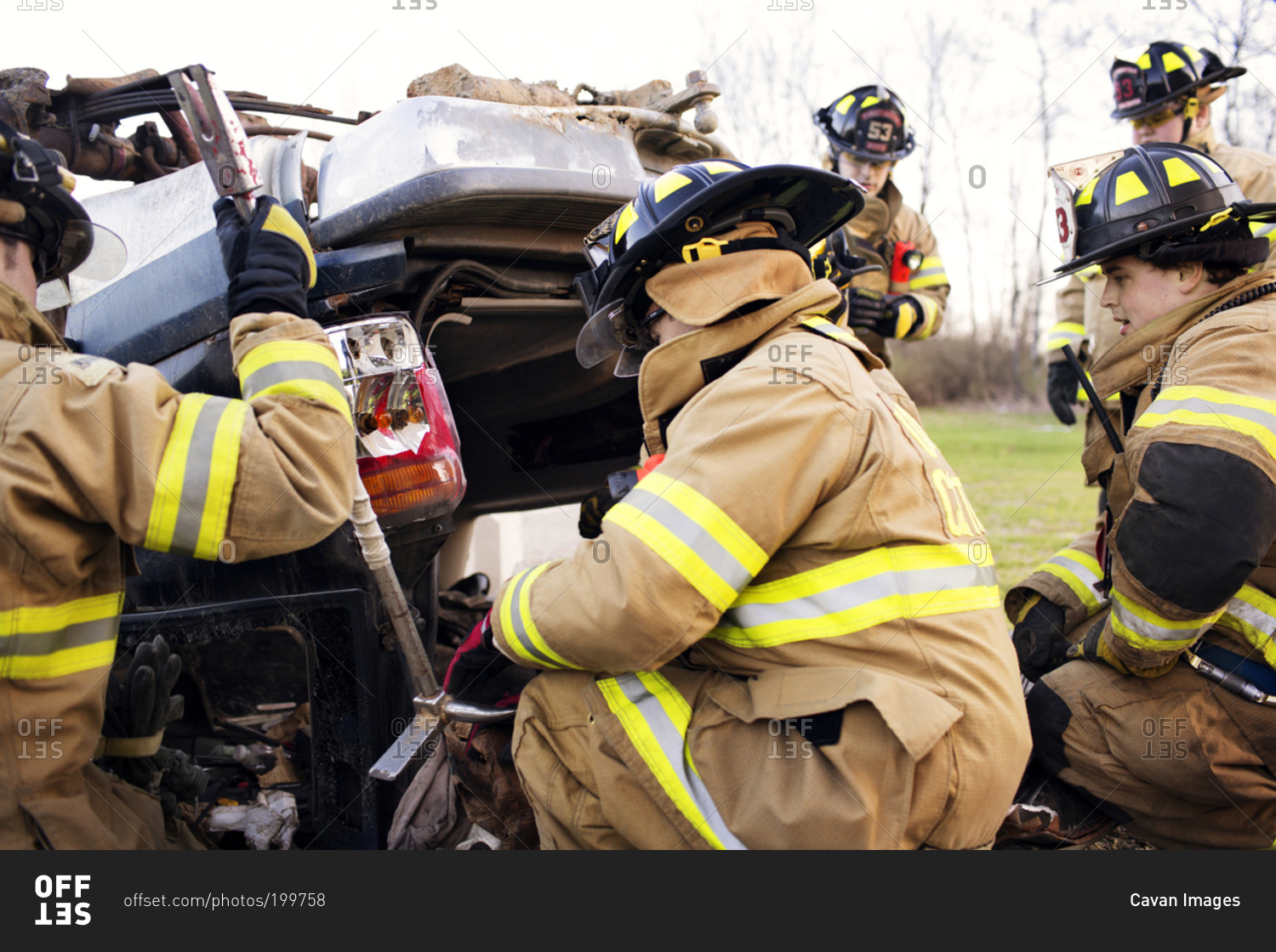 Firemen examine the wreckage of a car