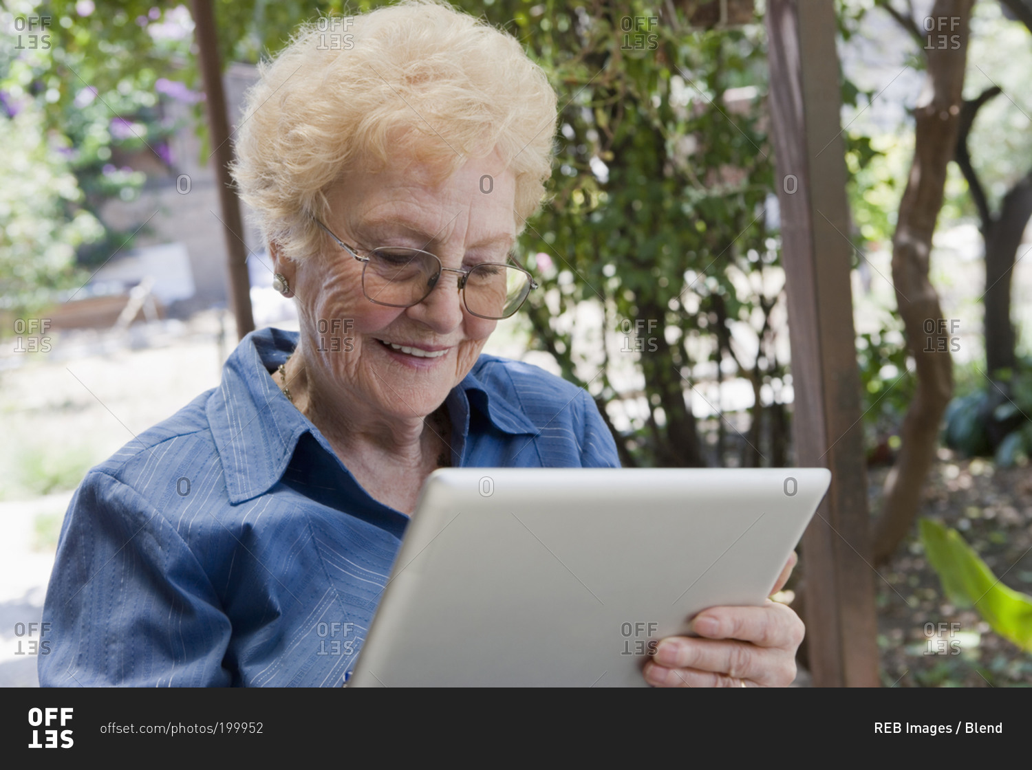 Elderly woman using tablet computer outdoors