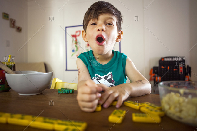 Young boy playing with dominoes at a kitchen table