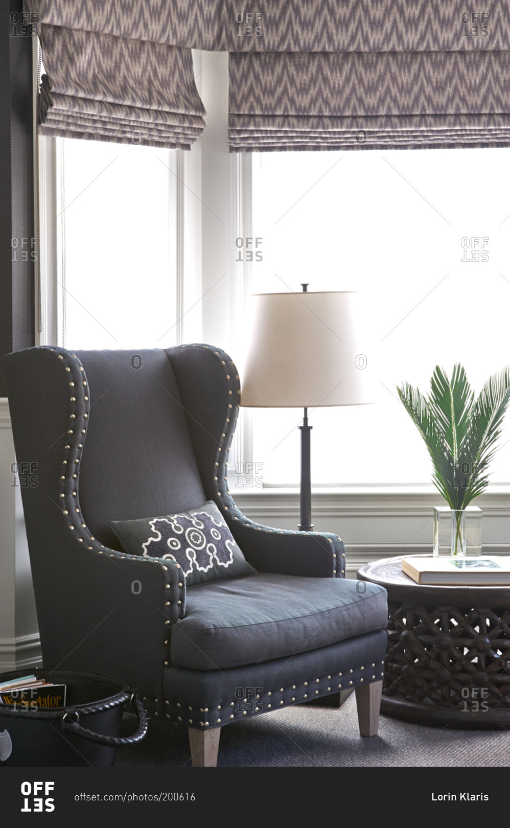 Gray wingback chair in front of bay windows