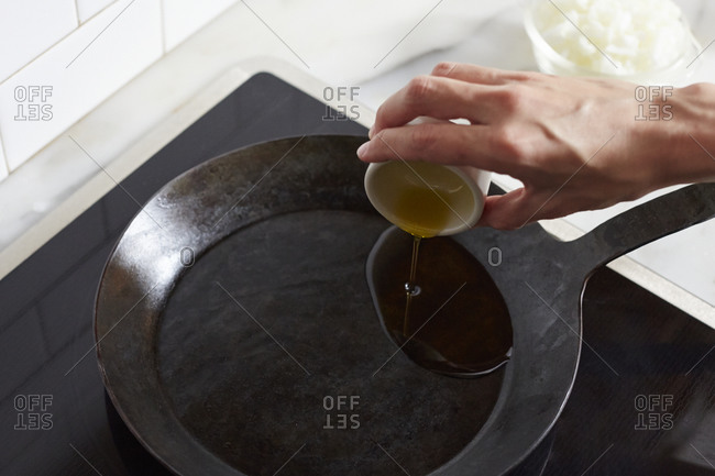 Pouring olive oil in pan to saut_ onions