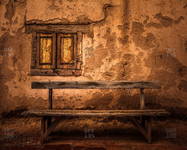 An old wooden bench in front of an adobe wall in Taos, New Mexico, USA
