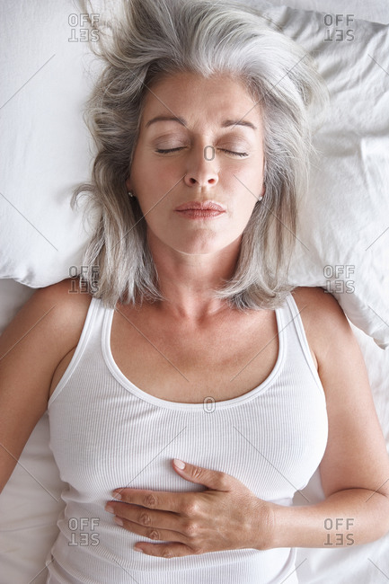 Woman with grey hair sleeping in bed