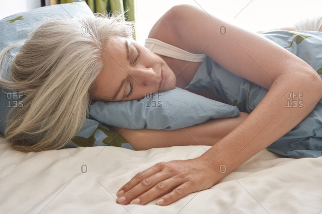 Woman with grey hair sleeping in bed