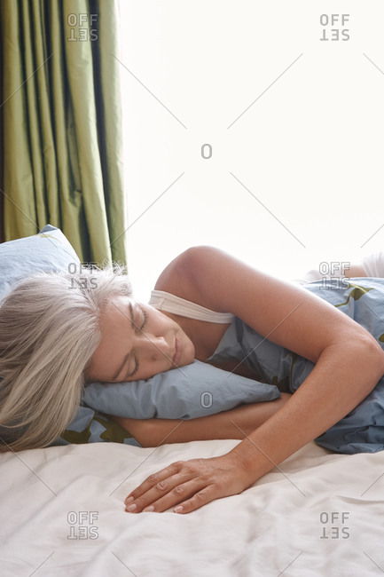 Woman with grey hair sleeping in bed